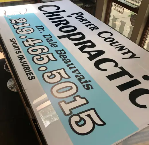 Large printed sign panel for a chiropractic office on a production table